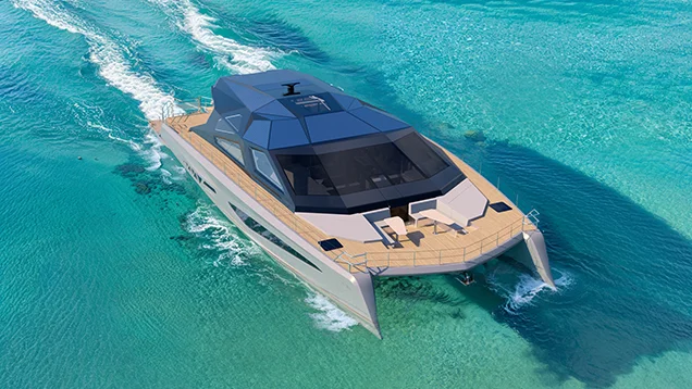 A luxury power catamaran cruising over crystal-clear turquoise waters near a tropical island, viewed from above